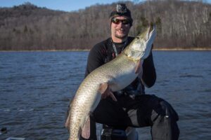 Jeremy on his boat holding a good sized musky