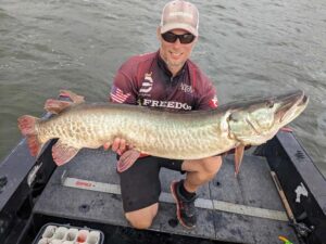 Jeremy Logan Newman of Fish Cowboyz holding a freshly caught Musky while on his boat.